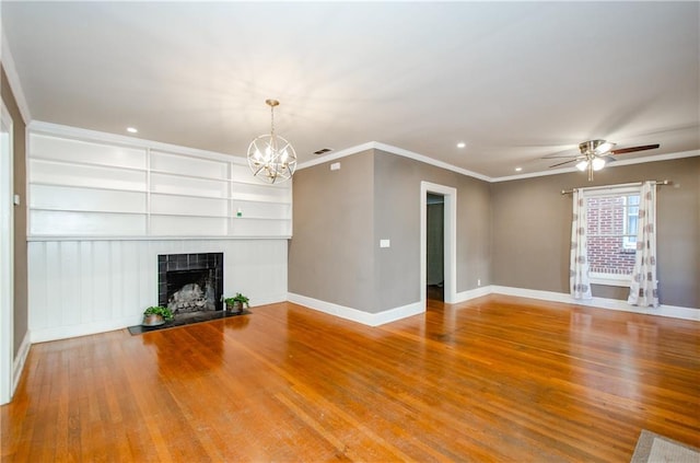 unfurnished living room featuring ornamental molding, hardwood / wood-style floors, built in features, a fireplace, and ceiling fan with notable chandelier