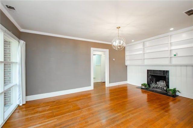 unfurnished living room with a notable chandelier, wood-type flooring, a fireplace, and crown molding