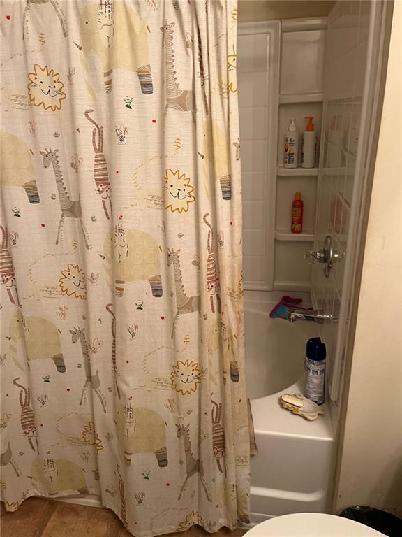 bathroom featuring shower / tub combo with curtain and toilet