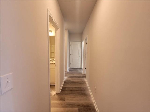 hallway with dark wood-type flooring and baseboards