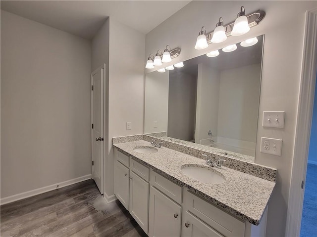 bathroom featuring double vanity, a sink, baseboards, and wood finished floors