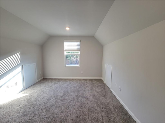 additional living space featuring carpet, lofted ceiling, and baseboards