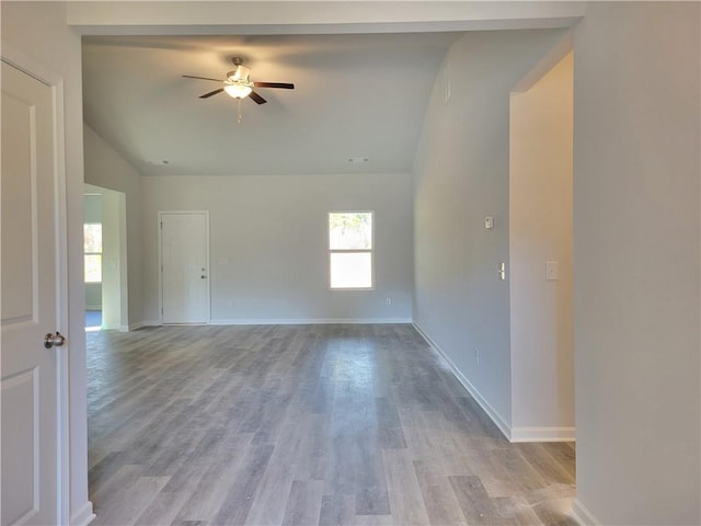 unfurnished room featuring visible vents, a ceiling fan, vaulted ceiling, wood finished floors, and baseboards