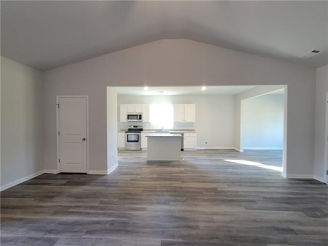 unfurnished living room featuring dark wood-style floors, vaulted ceiling, visible vents, and baseboards