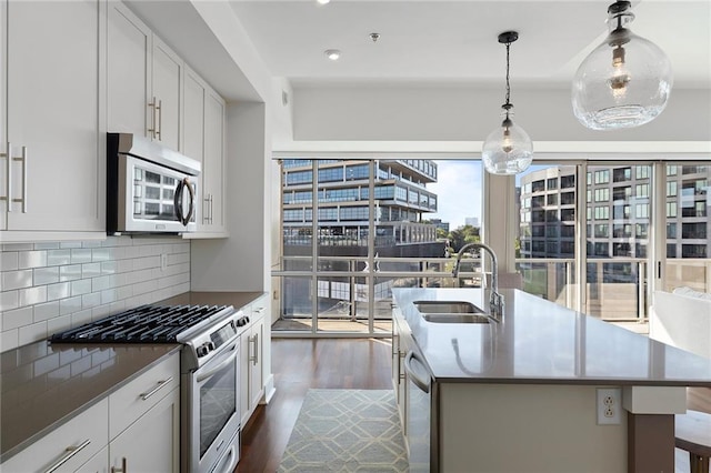 kitchen with appliances with stainless steel finishes, dark hardwood / wood-style flooring, white cabinetry, and sink