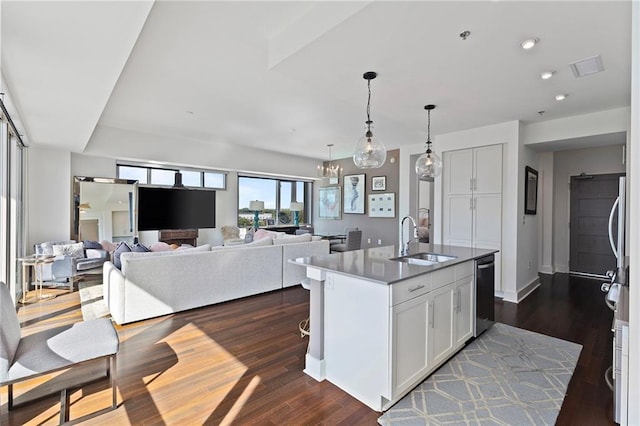 kitchen with dishwasher, dark wood-type flooring, an island with sink, and sink