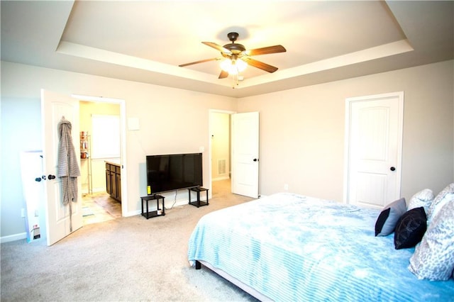 bedroom featuring light carpet, a raised ceiling, connected bathroom, and baseboards