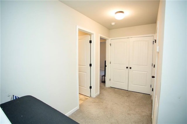 hall with light colored carpet and baseboards