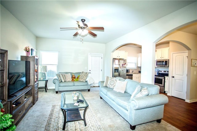 living room featuring arched walkways, a ceiling fan, and baseboards