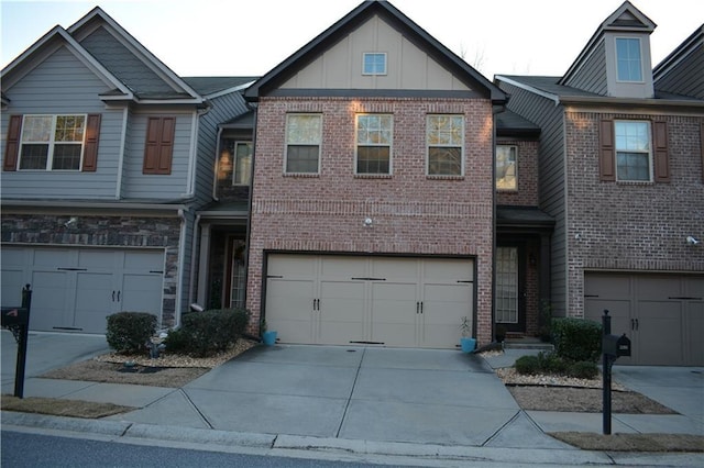 townhome / multi-family property featuring board and batten siding, concrete driveway, and brick siding