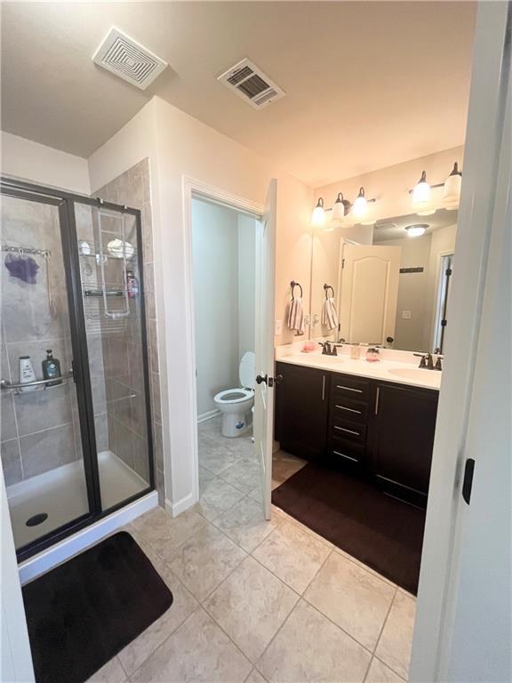 full bathroom with a sink, toilet, a shower stall, and visible vents