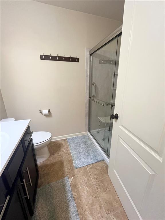 full bath featuring baseboards, toilet, a shower stall, and vanity