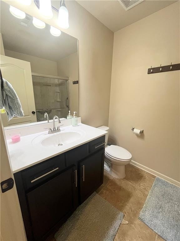 full bathroom featuring a stall shower, visible vents, baseboards, toilet, and vanity