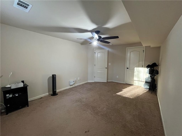 empty room featuring carpet floors, visible vents, ceiling fan, and baseboards