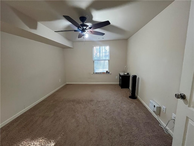 carpeted spare room featuring a ceiling fan and baseboards