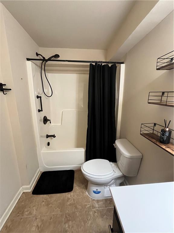 bathroom featuring shower / tub combo, vanity, toilet, and baseboards