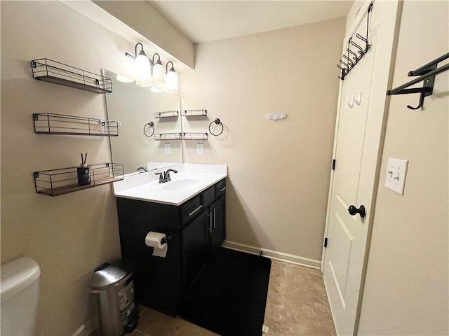 bathroom with toilet, baseboards, and vanity