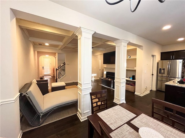 dining area featuring decorative columns, arched walkways, coffered ceiling, dark wood-style flooring, and a fireplace