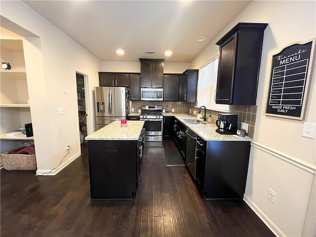 kitchen with dark wood-type flooring, stainless steel appliances, a sink, and a center island