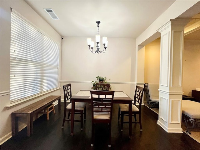 dining room with dark wood-type flooring, visible vents, decorative columns, and a notable chandelier