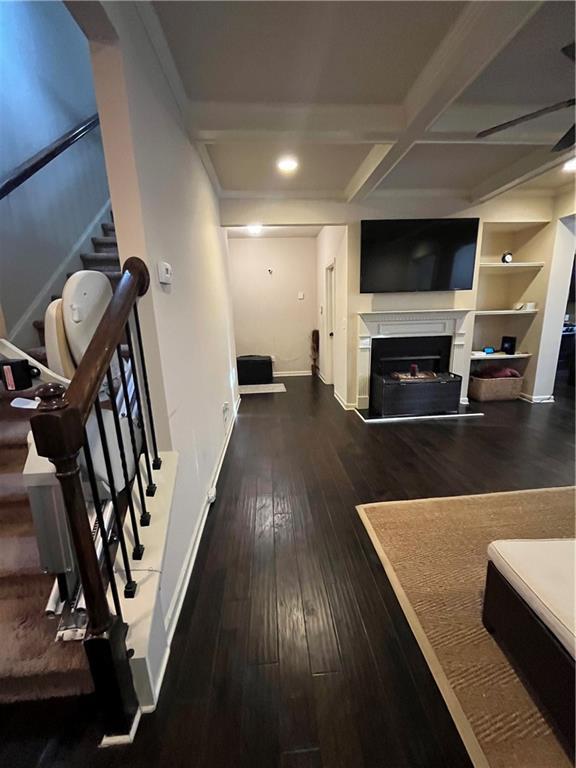 living area with stairs, a fireplace, coffered ceiling, baseboards, and hardwood / wood-style flooring