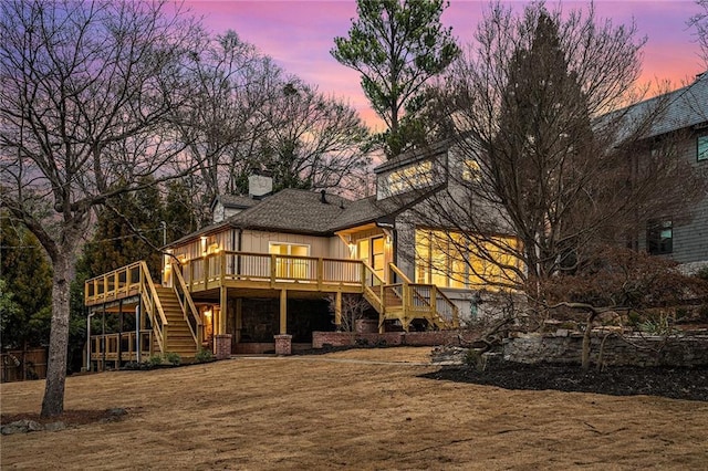 back of property at dusk featuring a chimney, stairway, a deck, and board and batten siding