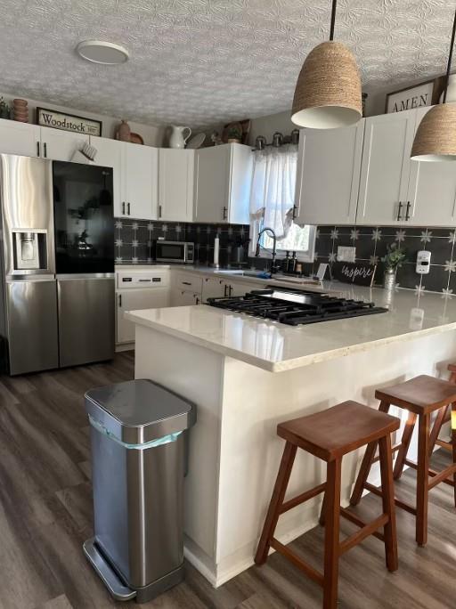 124 Dockside Downs Dr, Woodstock, GA 30189 - kitchen with stainless steel appliances, tasteful backsplash, white cabinetry, and a peninsula