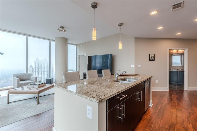 kitchen featuring pendant lighting, a kitchen island with sink, sink, stainless steel dishwasher, and dark hardwood / wood-style floors