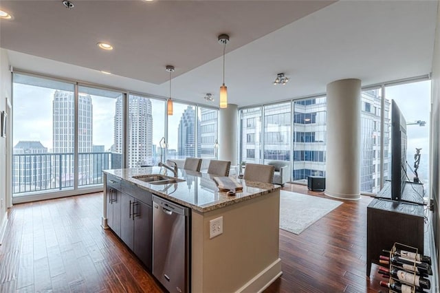 kitchen featuring dark hardwood / wood-style flooring, a kitchen island with sink, pendant lighting, and stainless steel dishwasher