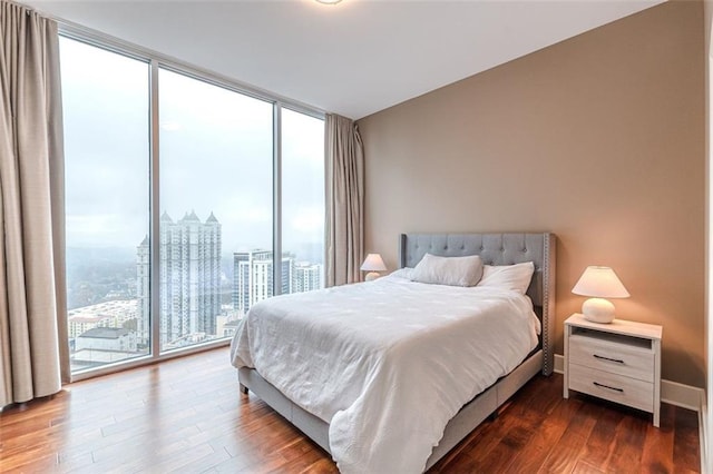 bedroom featuring access to exterior, floor to ceiling windows, and dark hardwood / wood-style flooring