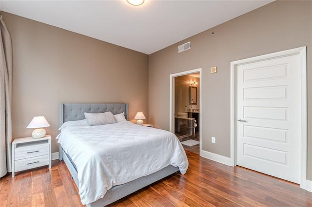 bedroom featuring hardwood / wood-style flooring and connected bathroom