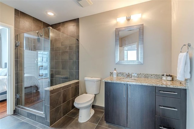 bathroom featuring tile patterned floors, a shower with door, vanity, and toilet