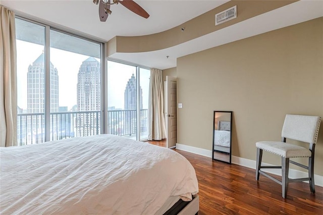 bedroom featuring access to exterior, dark hardwood / wood-style flooring, expansive windows, and ceiling fan