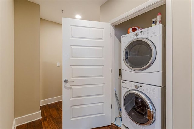 washroom with dark hardwood / wood-style flooring and stacked washer and dryer