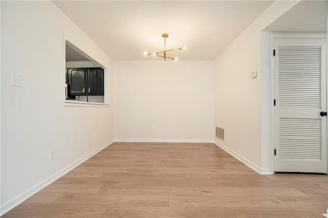 unfurnished dining area with an inviting chandelier and light hardwood / wood-style flooring