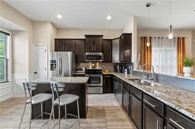 5440 Willow Oak Dr, Norcross, GA 30092 - kitchen featuring appliances with stainless steel finishes, light stone counters, a kitchen bar, tasteful backsplash, and a wainscoted wall