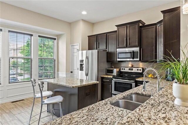 5440 Willow Oak Dr, Norcross, GA 30092 - kitchen featuring stainless steel appliances, light stone countertops, dark brown cabinets, tasteful backsplash, and recessed lighting