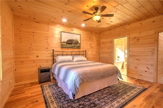 bedroom featuring ensuite bathroom, wood ceiling, wood walls, ceiling fan, and light hardwood / wood-style flooring