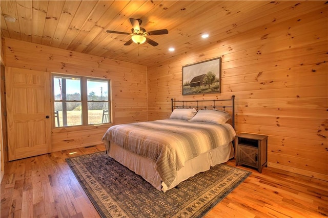 bedroom with wood walls, ceiling fan, wood ceiling, and light hardwood / wood-style flooring