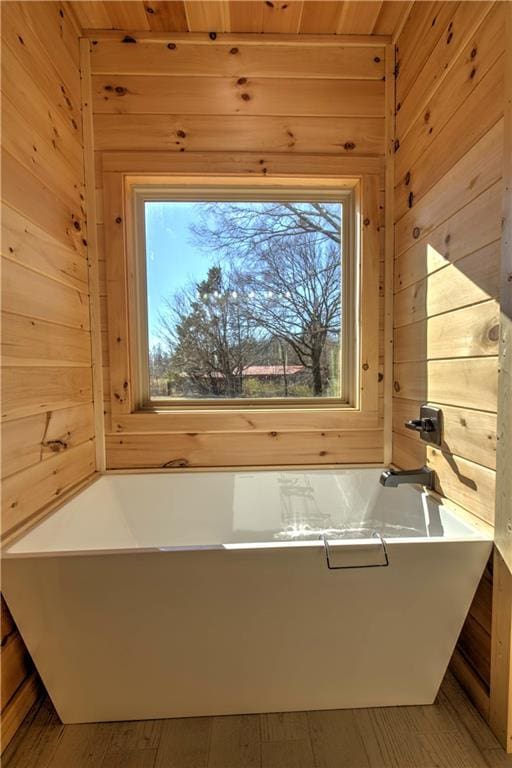 bathroom featuring a bathtub and wooden walls