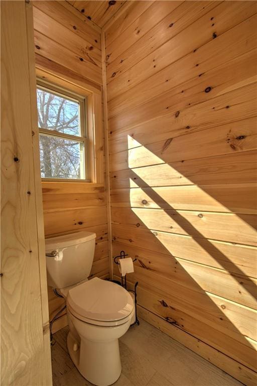 bathroom with toilet and wood walls