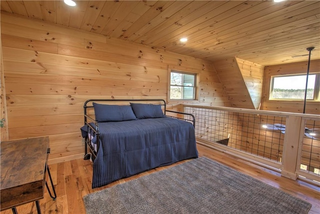 bedroom featuring wooden ceiling, multiple windows, wood walls, and light wood-type flooring