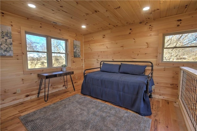 bedroom with wooden ceiling, wood walls, and light hardwood / wood-style flooring