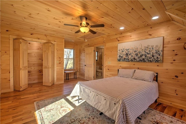 bedroom with ceiling fan, wood ceiling, wood walls, and light hardwood / wood-style flooring