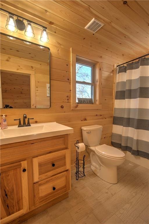 bathroom featuring toilet, walk in shower, wood walls, and vanity