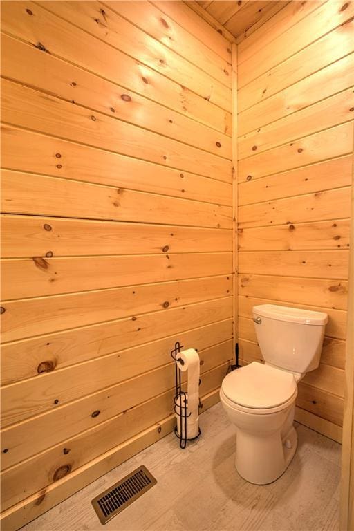 bathroom with toilet and wood walls