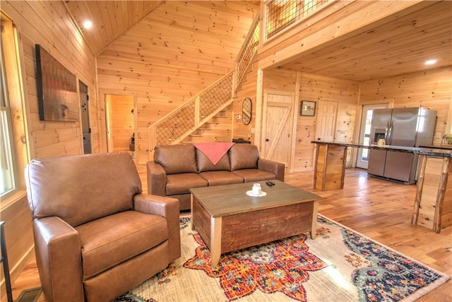 living room with lofted ceiling, wood ceiling, light hardwood / wood-style flooring, and wooden walls