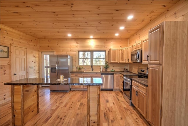 kitchen with a center island, sink, appliances with stainless steel finishes, a kitchen breakfast bar, and dark stone counters