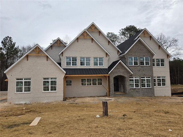 view of front of house with a standing seam roof, brick siding, and metal roof