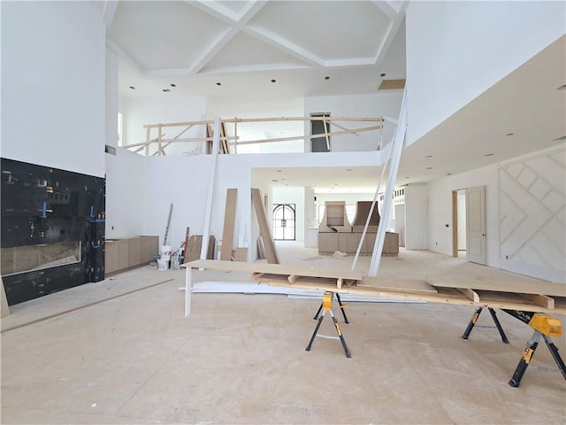 unfurnished living room featuring coffered ceiling and a towering ceiling